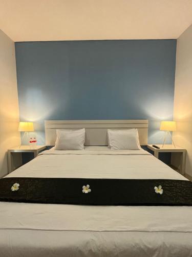 a bedroom with a large bed with two tables and two lamps at TOS Hotel & Convention Center Tangerang Powered by Archipelago in Tangerang