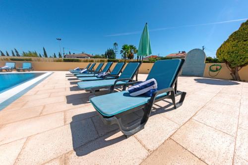 una fila di sedie a sdraio accanto alla piscina di Stunning Villa with Heated Pool, Garden, BBQ a Quarteira