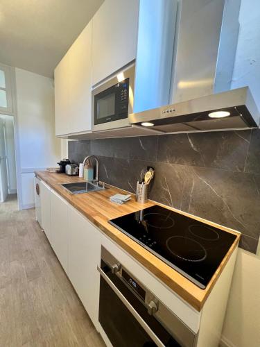 une cuisine avec un évier et une cuisinière four supérieur dans l'établissement Casa Grivel #1 - T2 avec Clim et Balcon - Centre Ville, à Brive-la-Gaillarde