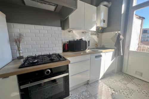 une cuisine avec des armoires blanches et un four à plaques de cuisson dans l'établissement Casa Zola #2 - Grand T2 central avec balcon proche gare, à Brive-la-Gaillarde