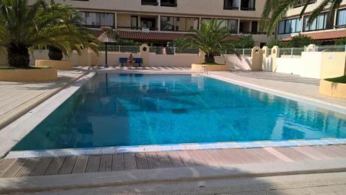 une grande piscine bleue avec des palmiers et un bâtiment dans l'établissement Vue sur les voiliers, à Gruissan