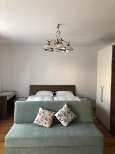 a bedroom with a bed with a blue couch with pillows at Sobe apartma Dobe in Bled