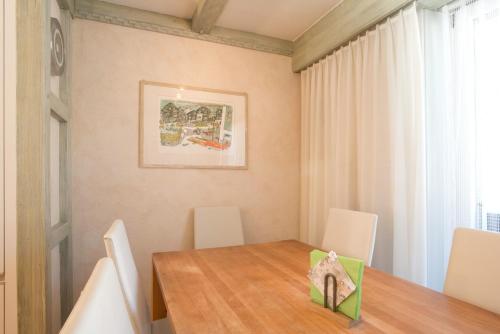 a dining room with a wooden table and white chairs at Bernerhof Residence in Grindelwald