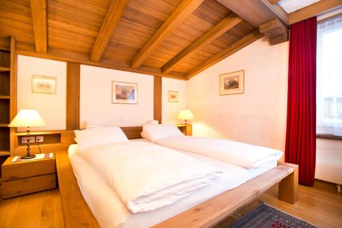 ein großes Bett in einem Zimmer mit einem roten Vorhang in der Unterkunft Bernerhof Residence in Grindelwald