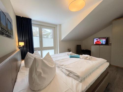 ein großes weißes Bett in einem Zimmer mit einem TV in der Unterkunft Strandvilla Baabe 10 HERZMUSCHEL in Baabe