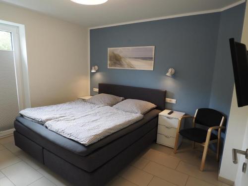 a bedroom with a bed and a chair in it at Kirschgarten 2 - Möwennest in Kellenhusen