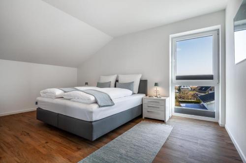 a white bedroom with a large bed and a window at Casa Báltica Haffkrug in Haffkrug