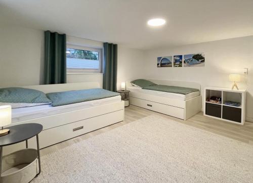 a bedroom with two beds and a table and a window at Lütte Deern in Kellenhusen