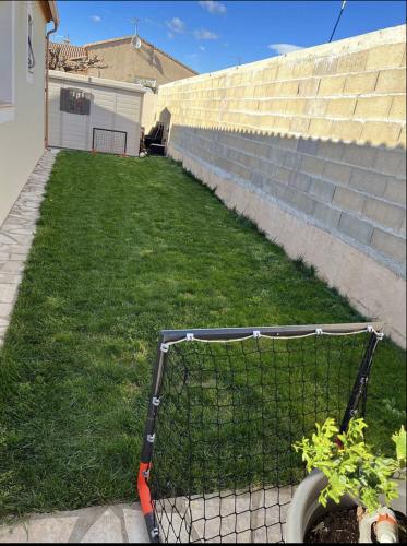 une voiturette de golf dans l'herbe à côté d'un bâtiment dans l'établissement Maison vacances, à Gallargues-le-Montueux