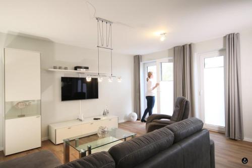 a living room with a couch and a person looking out the window at Störtebeker 4 in Kellenhusen