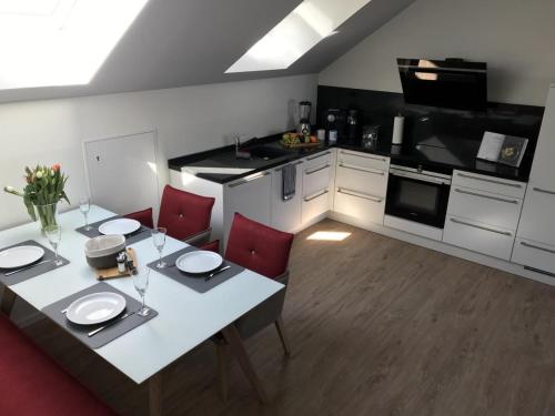 a kitchen with a white table and red chairs at Sonnengarten 20 - Heimathafen in Kellenhusen