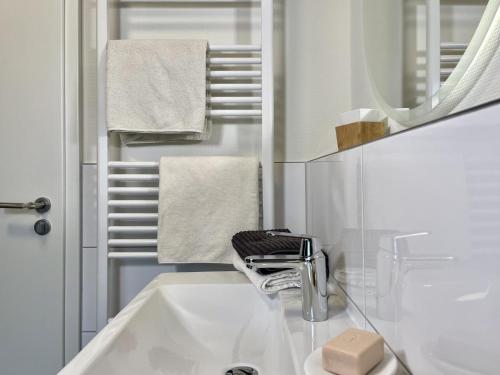 a white bathroom with a sink and a mirror at Lönnegarden - Bootsmann in Kellenhusen