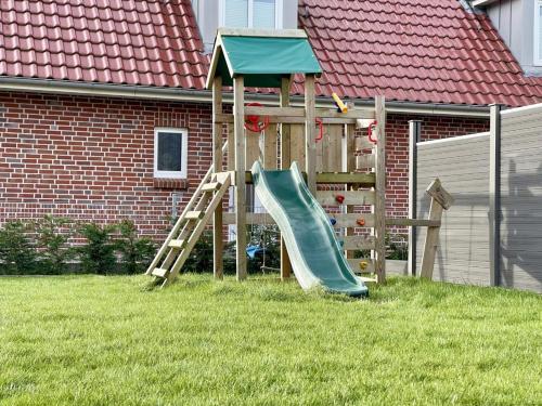 a playground with a slide in a yard at Lönnegarden - Bootsmann in Kellenhusen