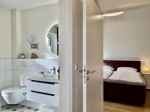 a white bathroom with a sink and a bed at Lönnegarden - Tante Emma in Kellenhusen