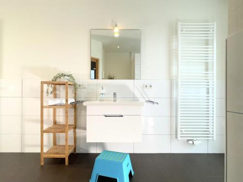 un bagno con un lavandino, uno specchio e uno sgabello di Quartier Hohe Geest 2 a Sahlenburg