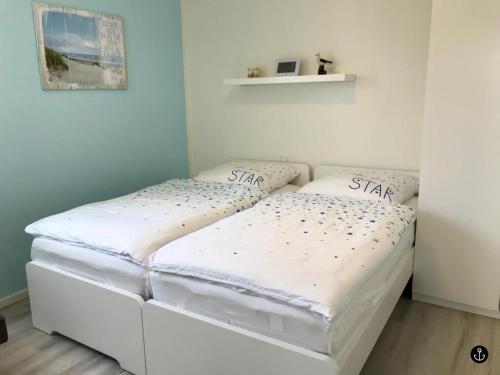 a white bed in a room with two pillows on it at Sonnengarten 4 - Sonnenveranda in Kellenhusen