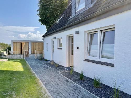 a white house with a walkway next to a yard at Deichquartier in Oesterdeichstrich