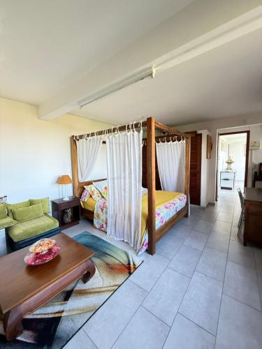 a bedroom with a bed and a couch and a table at Emplacement idéal 3 mn plage ! in Les Trois-Îlets