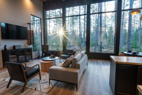un soggiorno con divano, sedie e finestre di Brand New Black Fox Cabin with Private Nordic Spa a Sprucedale