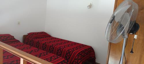 a room with a bed and a fan on the wall at El nuevo amanecer mar de ajó in Mar de Ajó