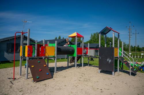 a playground with colorful play equipment in the sand at Bałtyckie Klimaty in Gąski