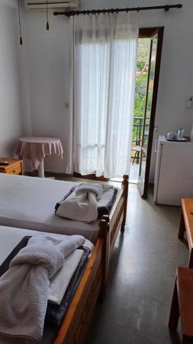 a bedroom with two beds and a large window at Hotel Rena in Agios Kirykos