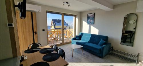 a living room with a blue couch and a table at Apartament Oliwia in Kluszkowce