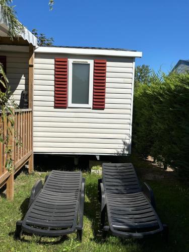 two chaise lounges in the grass in front of a house at Mobil-home 40m2, camping les Charmettes 4 étoiles La Palmyre 4-6 personnes-2 chambres dont 1 suite parentale-2 salles de bain in Les Mathes