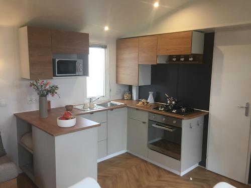 a kitchen with white cabinets and a stove top oven at Mobil-home 40m2, camping les Charmettes 4 étoiles La Palmyre 4-6 personnes-2 chambres dont 1 suite parentale-2 salles de bain in Les Mathes