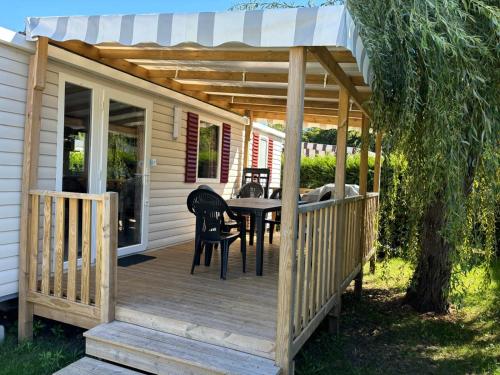 a wooden deck with a table and a pergola at Mobil-home 40m2, camping les Charmettes 4 étoiles La Palmyre 4-6 personnes-2 chambres dont 1 suite parentale-2 salles de bain in Les Mathes