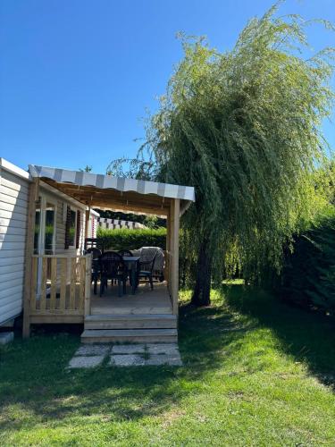 a pavilion with a table and chairs under a tree at Mobil-home 40m2, camping les Charmettes 4 étoiles La Palmyre 4-6 personnes-2 chambres dont 1 suite parentale-2 salles de bain in Les Mathes