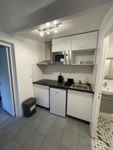 une petite cuisine avec des armoires blanches et un évier dans l'établissement Studio jardin proche de transport, à Gagny