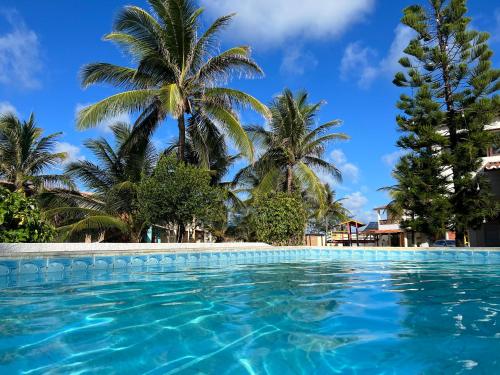 a swimming pool with palm trees in the background at Casa de praia - Búzios in Nísia Floresta