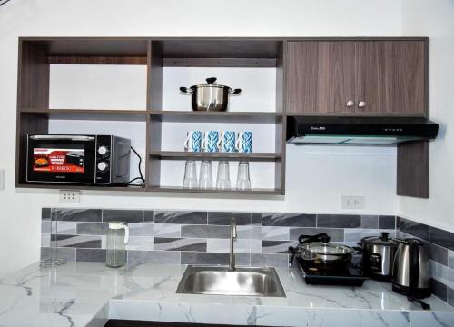 a kitchen counter with a sink and a microwave at Casa Bugambilia Door 2 in Balamban