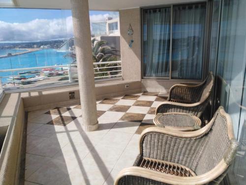 a balcony with three chairs and a view of the ocean at San Alfonso del Mar Departamentos in Algarrobo