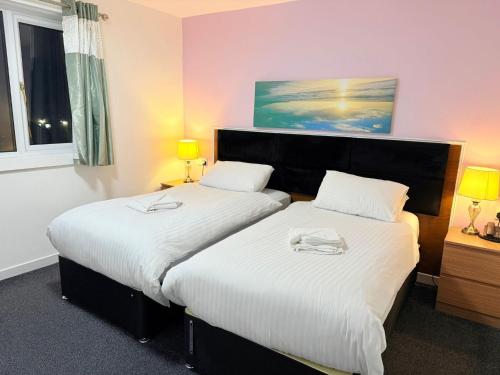 two beds in a small room with two lamps at County Hotel in Helensburgh