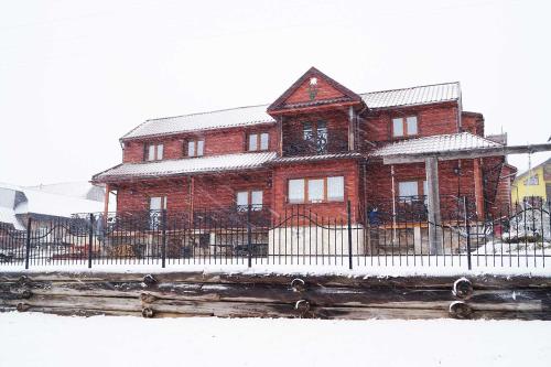 a red brick house with a fence in front of it at Penzión Goraľka in Ždiar