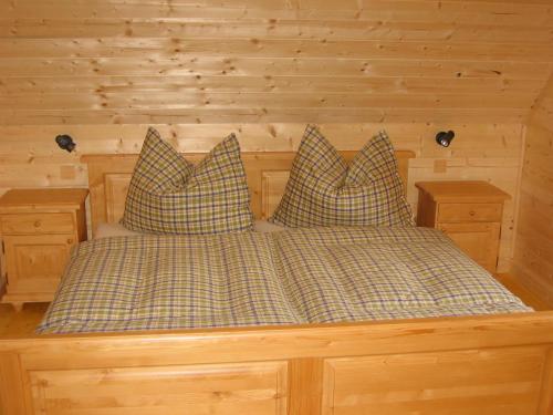 Cama en habitación de madera con 2 almohadas en Feriendorf Lassing en Göstling an der Ybbs