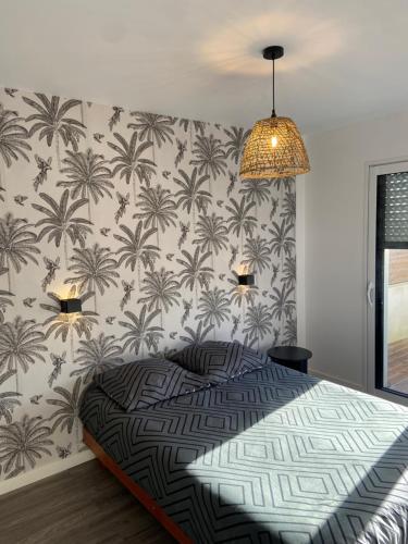 - une chambre avec un lit et du papier peint orné de palmiers dans l'établissement Maison au calme, à Cléguer