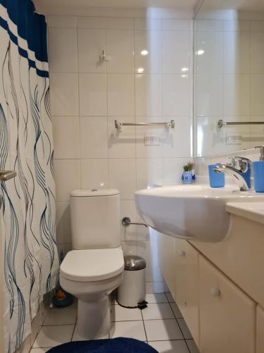 a white bathroom with a toilet and a sink at San Alfonso del Mar Departamentos in Algarrobo