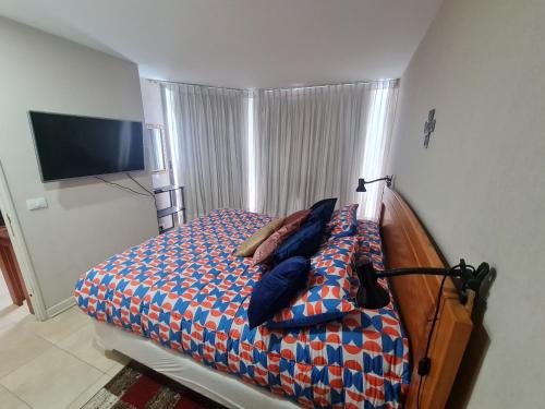 a bedroom with a bed with pillows and a television at San Alfonso del Mar Departamentos in Algarrobo