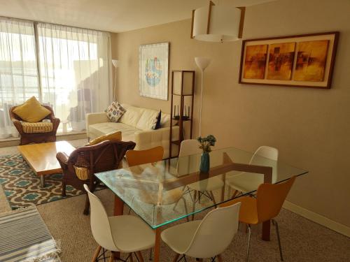 a living room with a glass table and chairs at San Alfonso del Mar Departamentos in Algarrobo