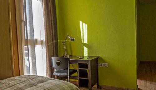 a green room with a desk with a lamp and a bed at Mirador El Silo in Bello