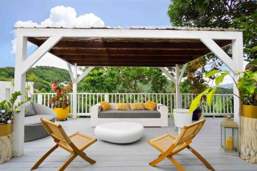 een prieel met een bank en stoelen op een terras bij Villa Pitayaa in Sainte-Luce