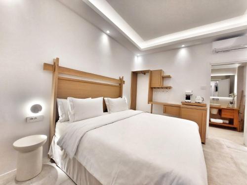 a bedroom with a large white bed and a bathroom at DelMar Suites Syros in Finikas