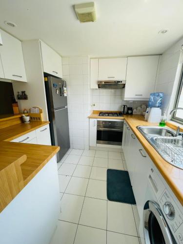 a kitchen with white cabinets and a stainless steel refrigerator at San Alfonso del Mar Departamentos in Algarrobo