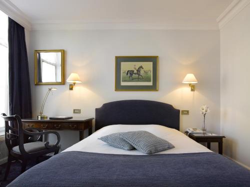 a bedroom with a bed with a chair and a desk at Hotel Damier Kortrijk in Kortrijk