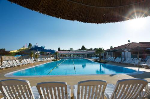 a large swimming pool with chairs around it at MOBIL-HOMES LES CHARMETTES 4 Etoîles in Les Mathes