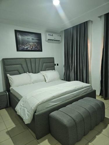 1 dormitorio con 1 cama grande y 1 reposapiés grande en Molarans Place, en Abuja