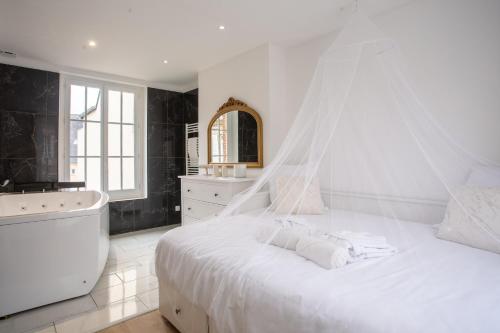 - une chambre blanche avec un grand lit et une baignoire dans l'établissement L'amour vrai - Love room -T2 Elégant et Romantique, à Abbeville